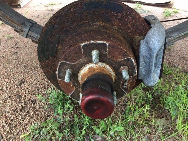 A Rusty Brake Disc Is Sitting In The Grass — Bohle Welding & Trailer Repairs In Bohle, QLD