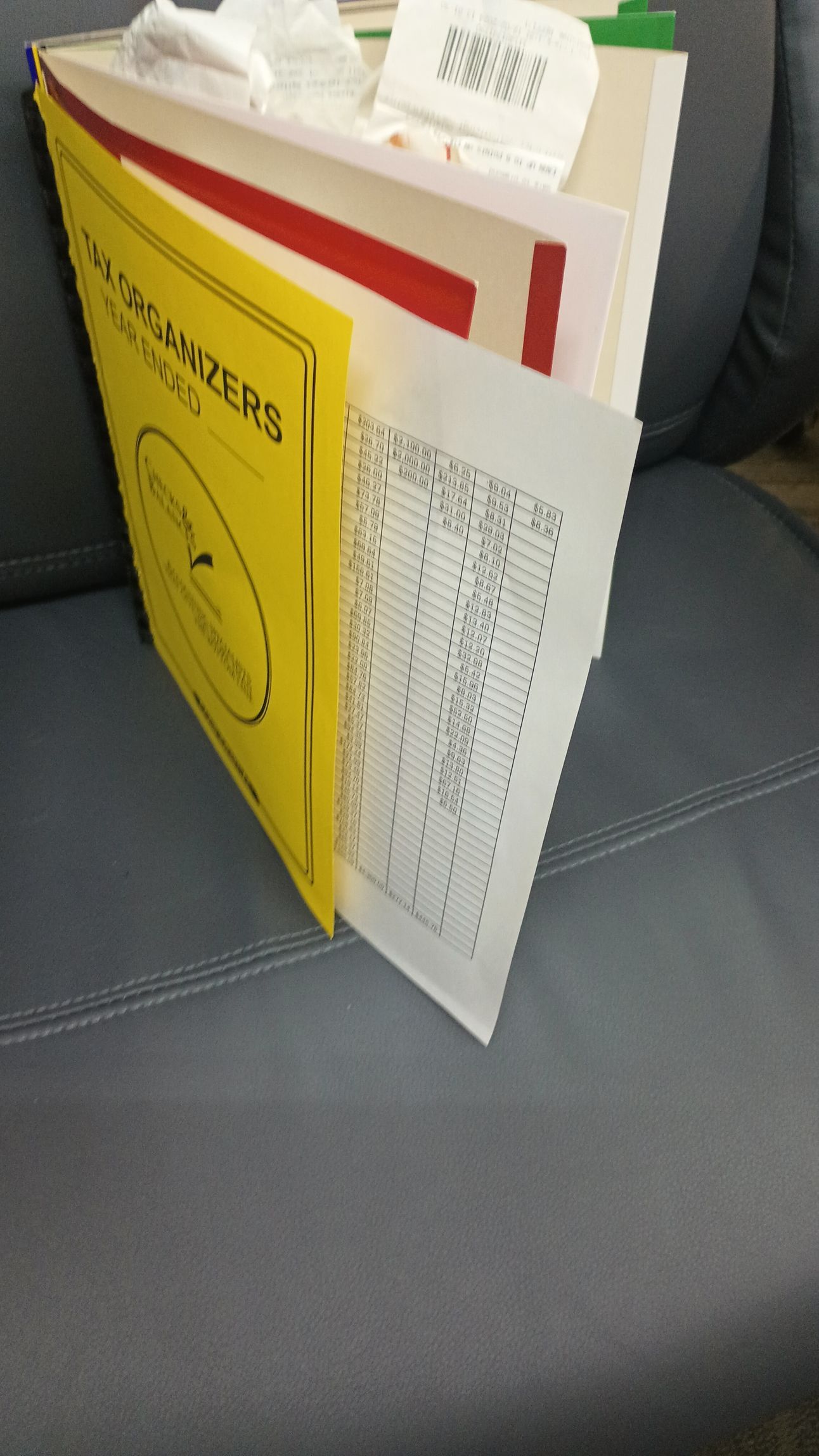 Yellow booklet and white sheet music folder standing on a gray couch seat.