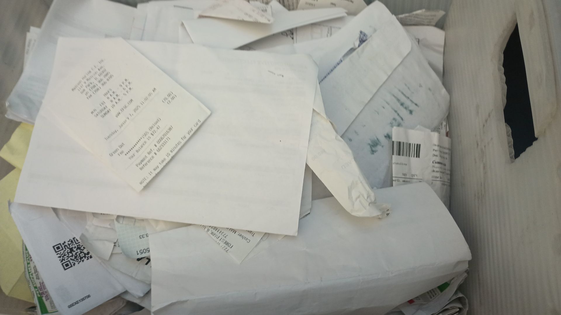 Pile of white shipping envelopes and packages stacked in a container or bin.