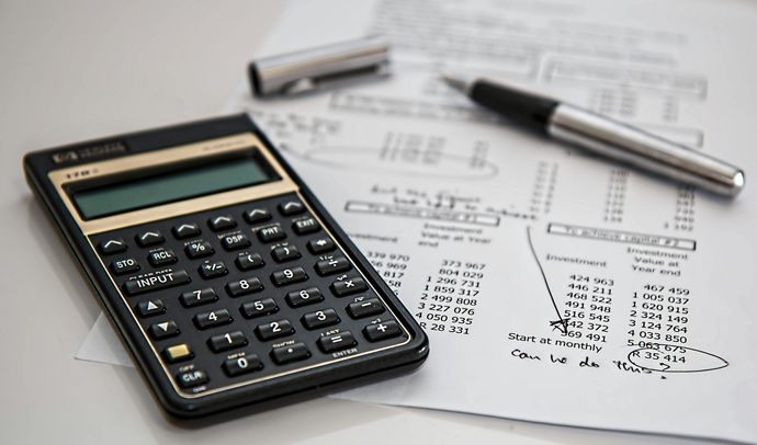 Calculator and pen on top of financial paperwork.