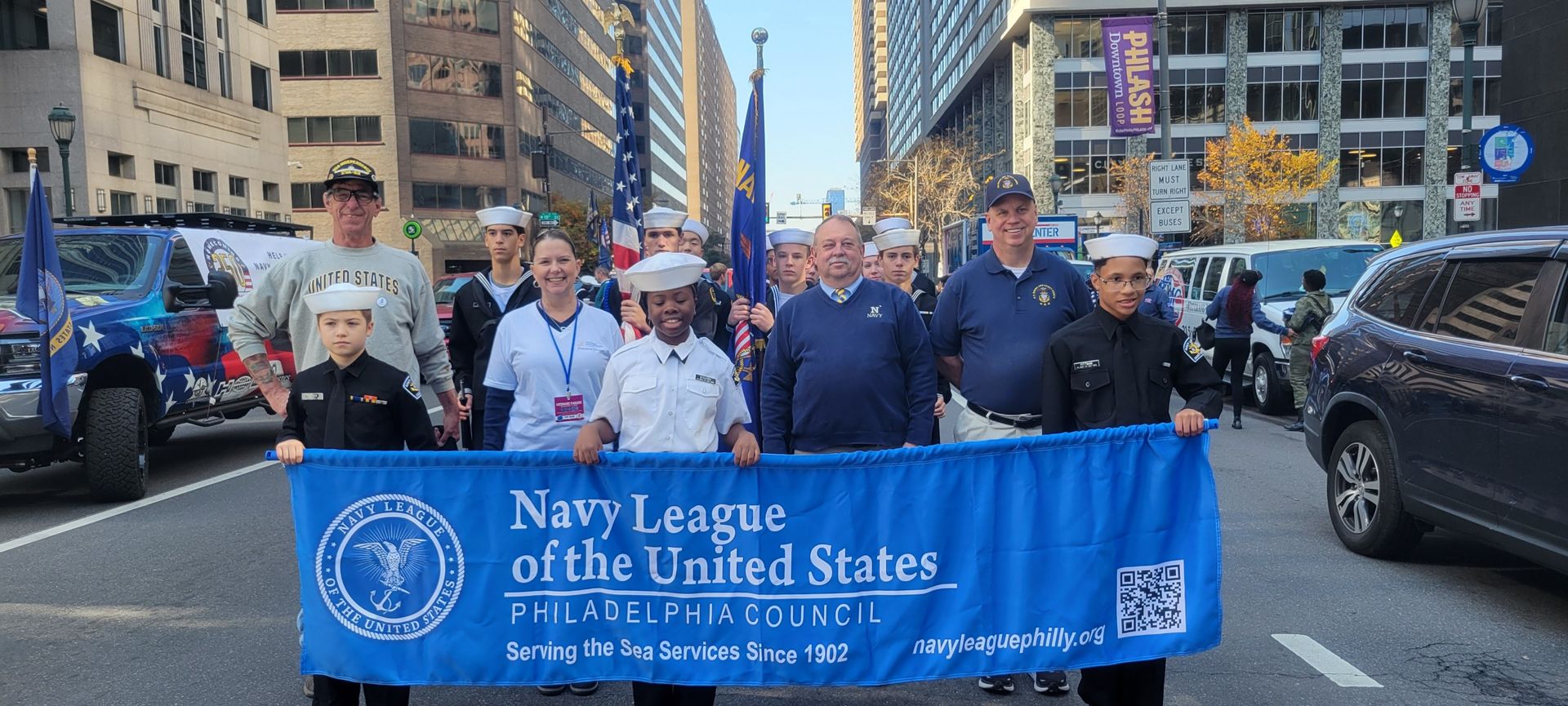 A group of people are holding a blue banner that says Navy League of The United States