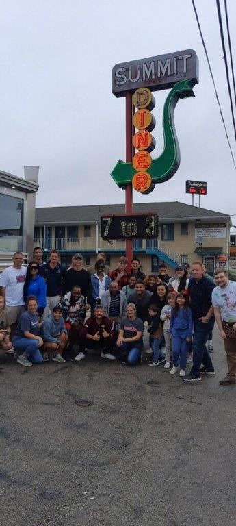 A group of people posing in front of a summit sign