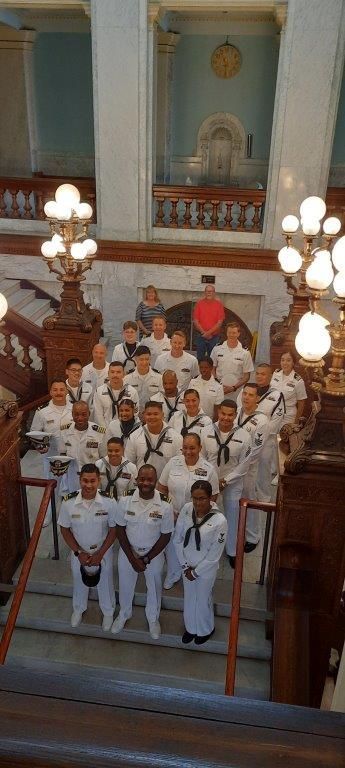 A large group of men in white uniforms are posing for a picture in a building.