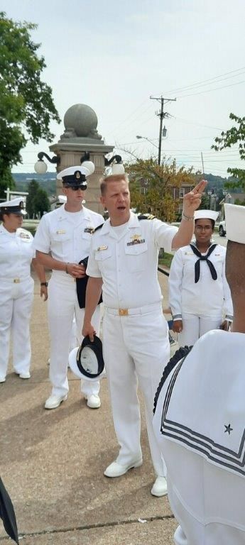 A group of men in white uniforms are standing on a sidewalk.