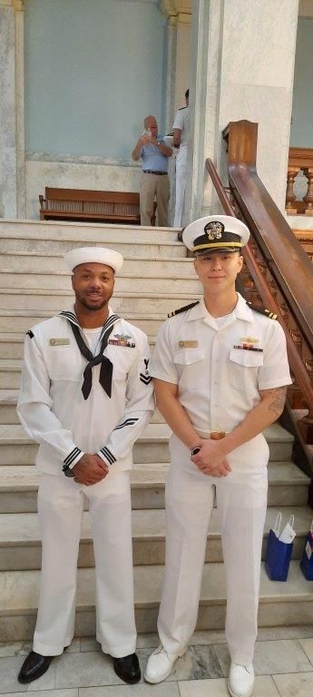 Two men in white uniforms are standing next to each other on a set of stairs.