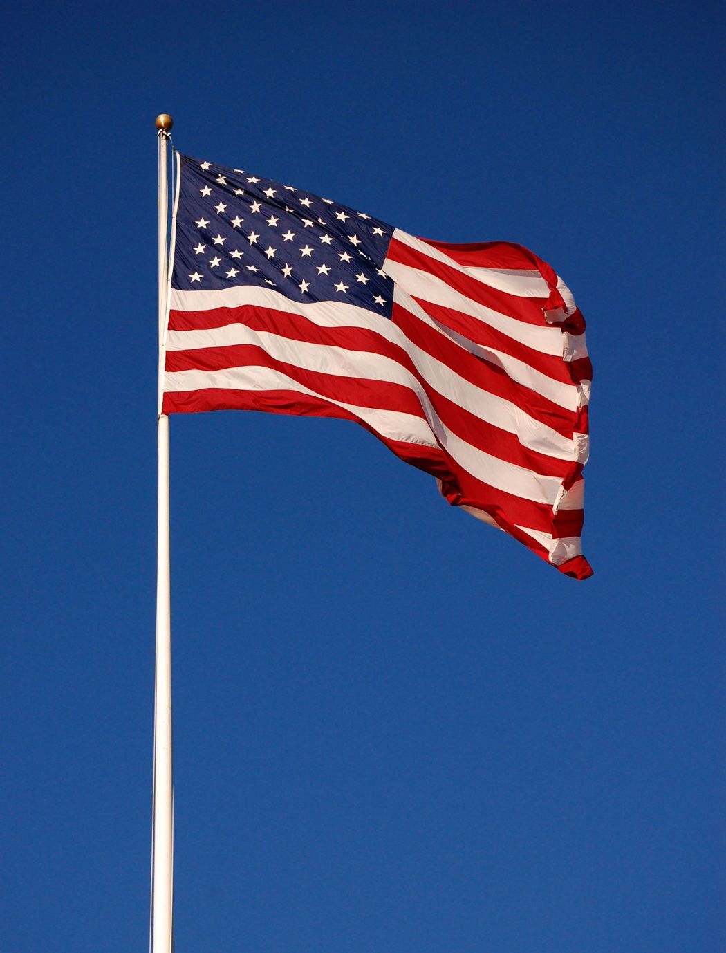 An American Flag Is Waving in The Wind Against a Blue Sky