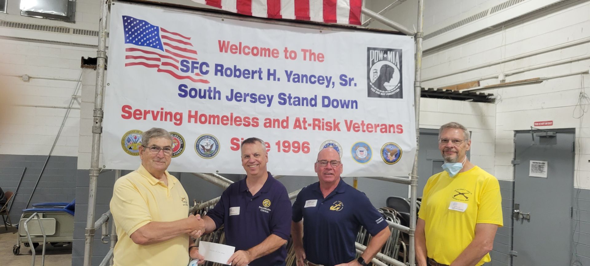 Four men are standing in front of a sign that says welcome to the spc robert h. yardley sr. south jersey stand down
