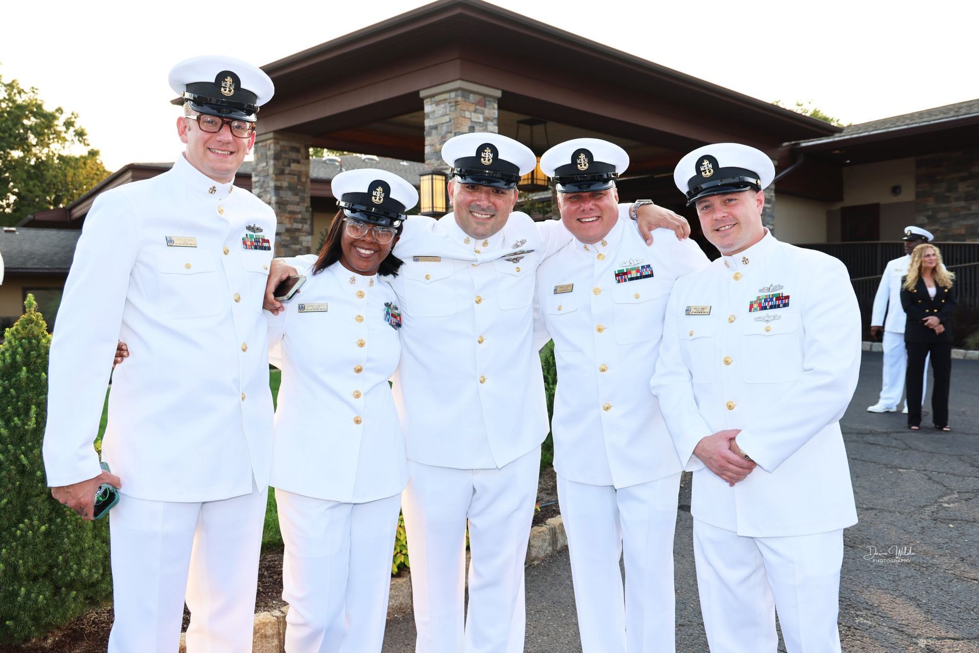 A group of people in white uniforms are posing for a picture in front of a building.