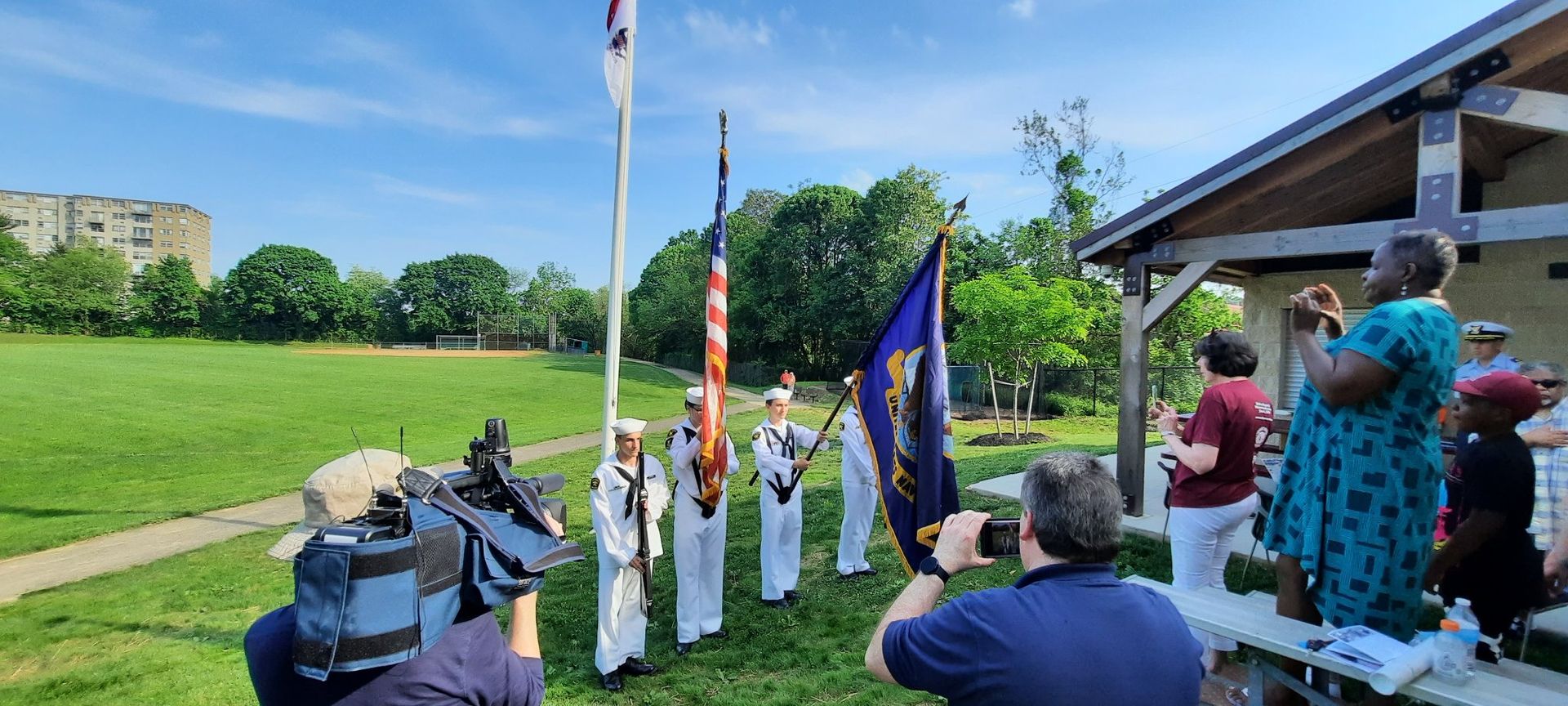 A group of people are standing in front of a flag pole.