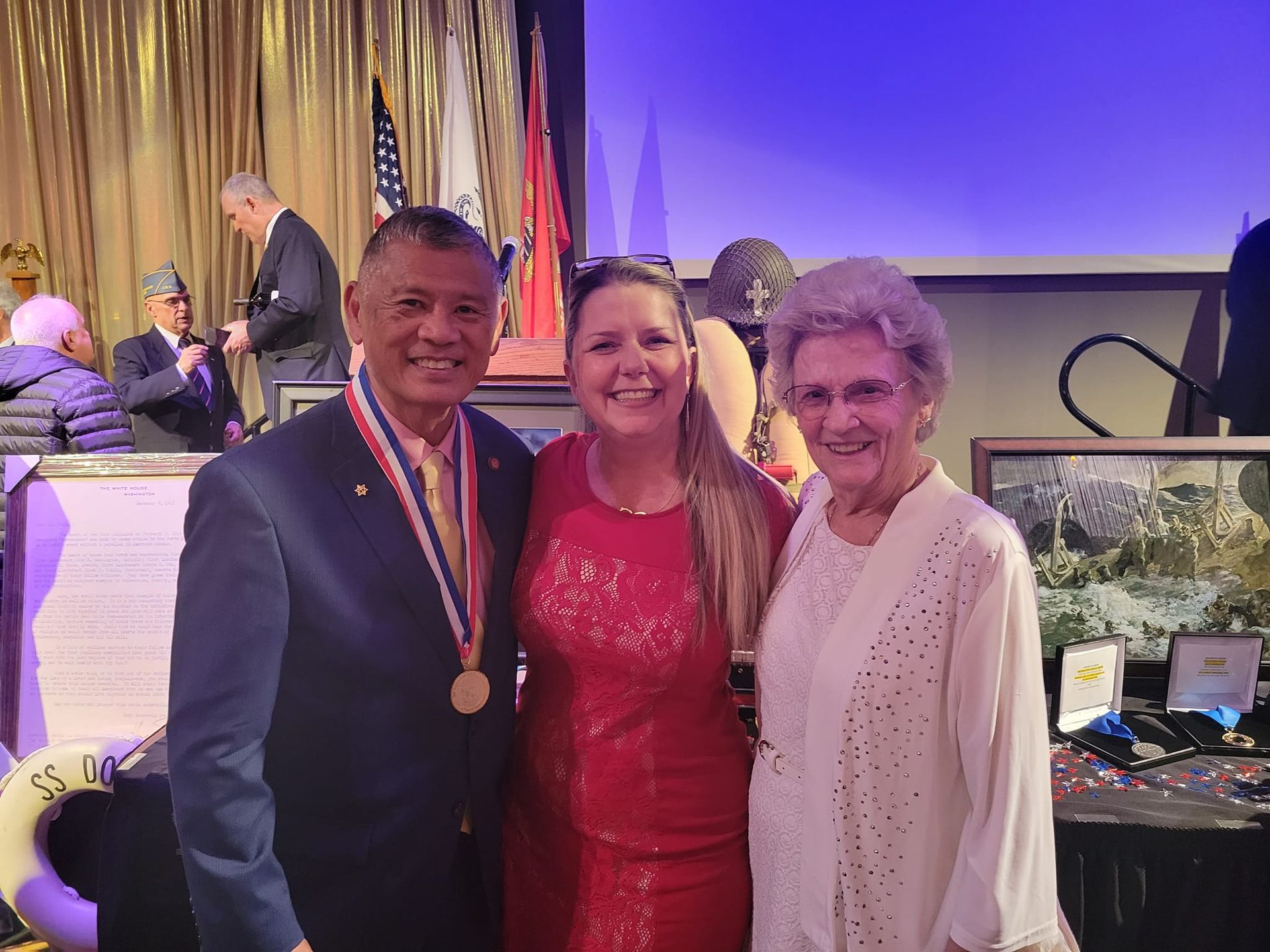 A man and two women are posing for a picture in a room . the man is wearing a medal around his neck.