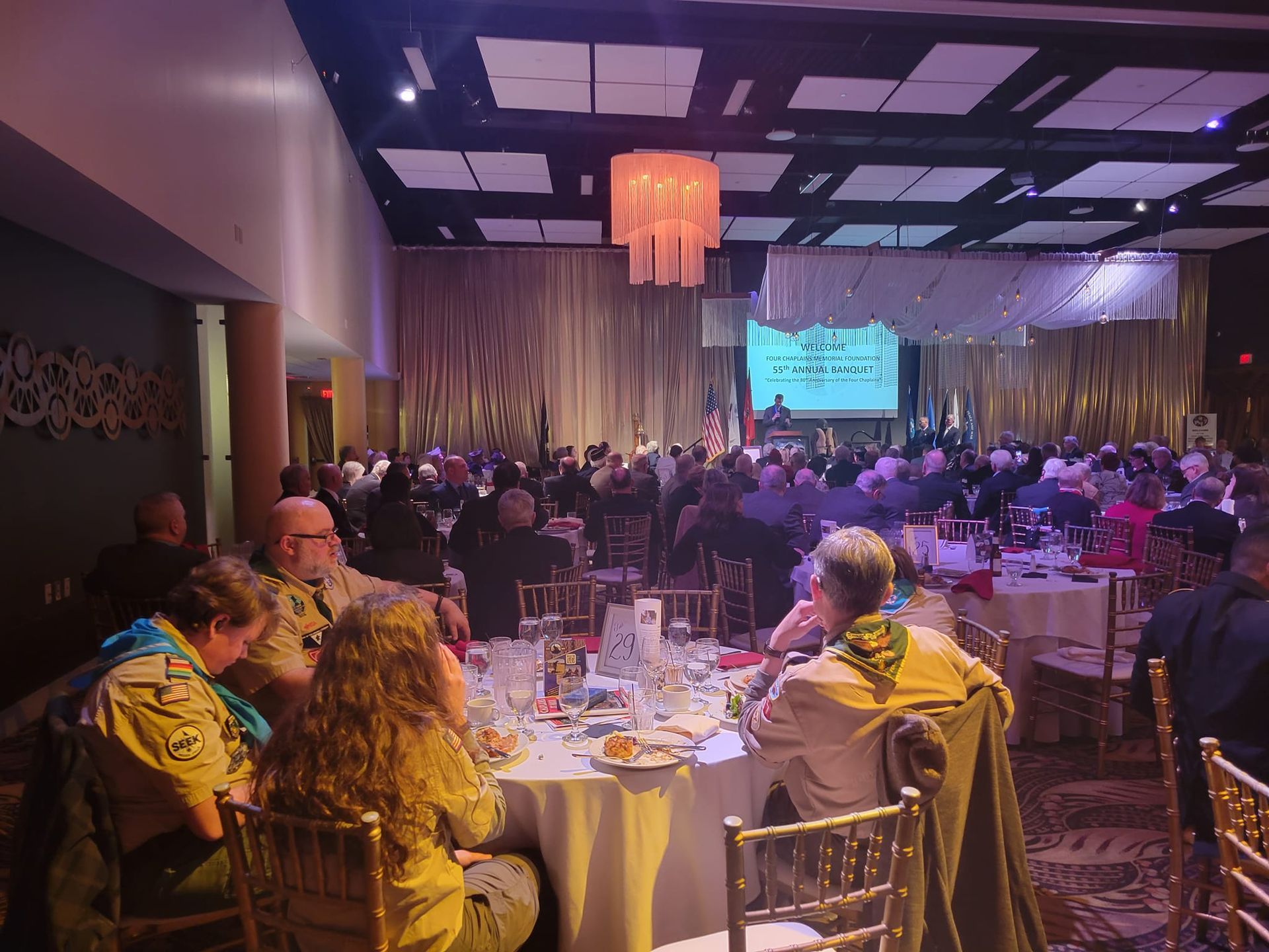 A large group of people are sitting at tables in a large room.