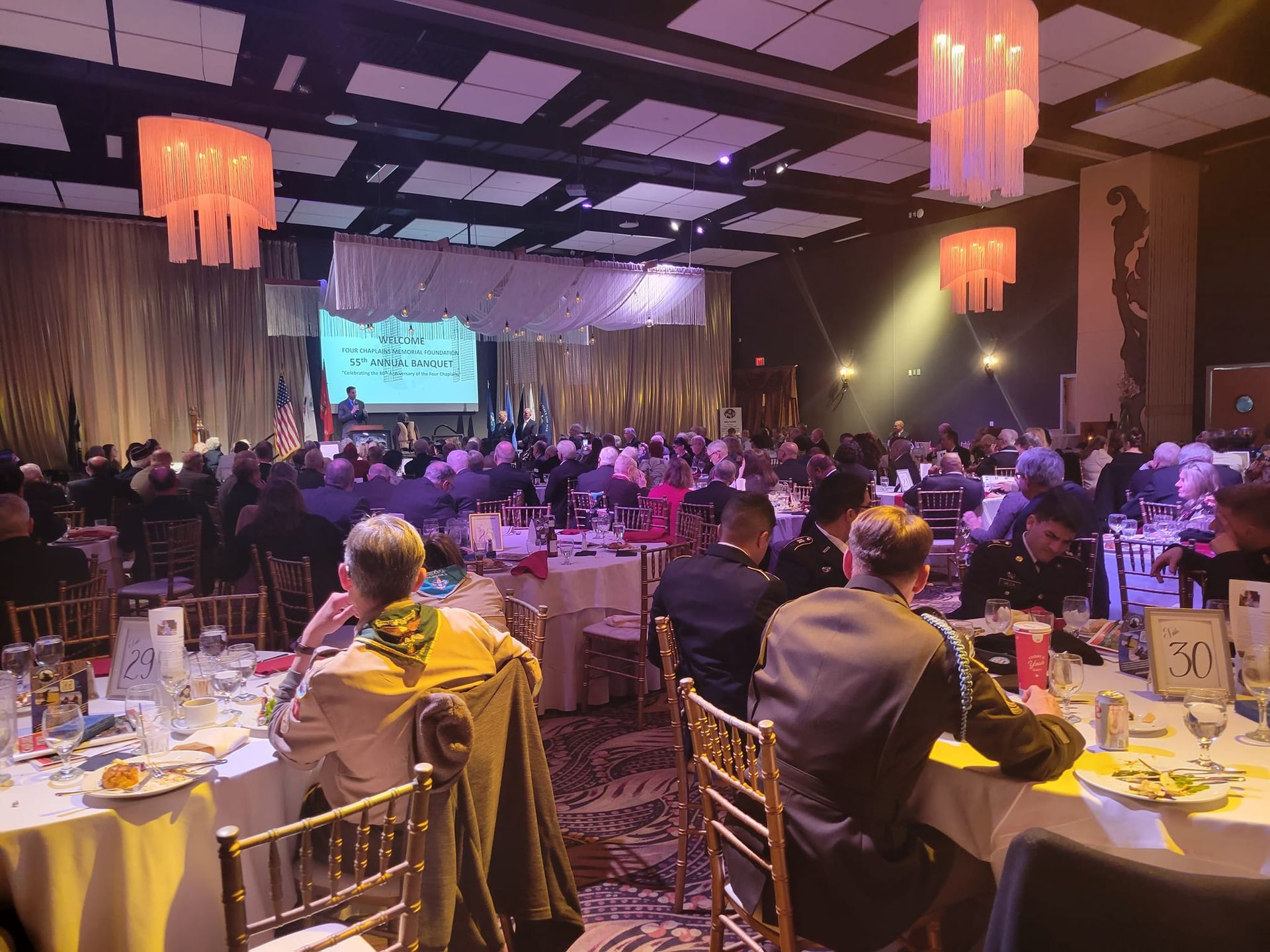 A large group of people are sitting at tables in a large room.