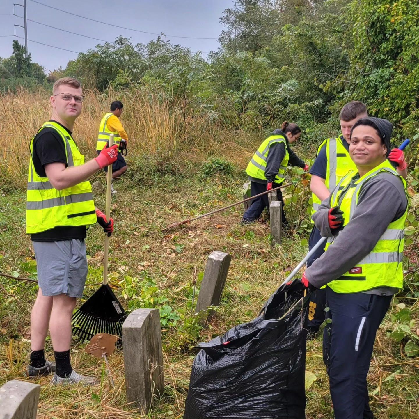 A group of people in yellow vests are working in a cemetery