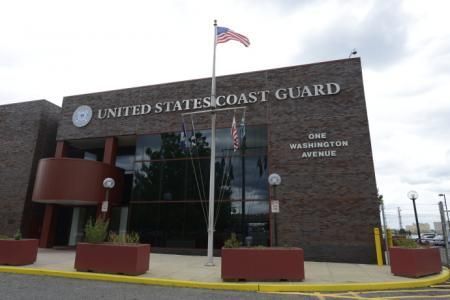 A United States Coast Guard building with a flag on a pole in front of it.