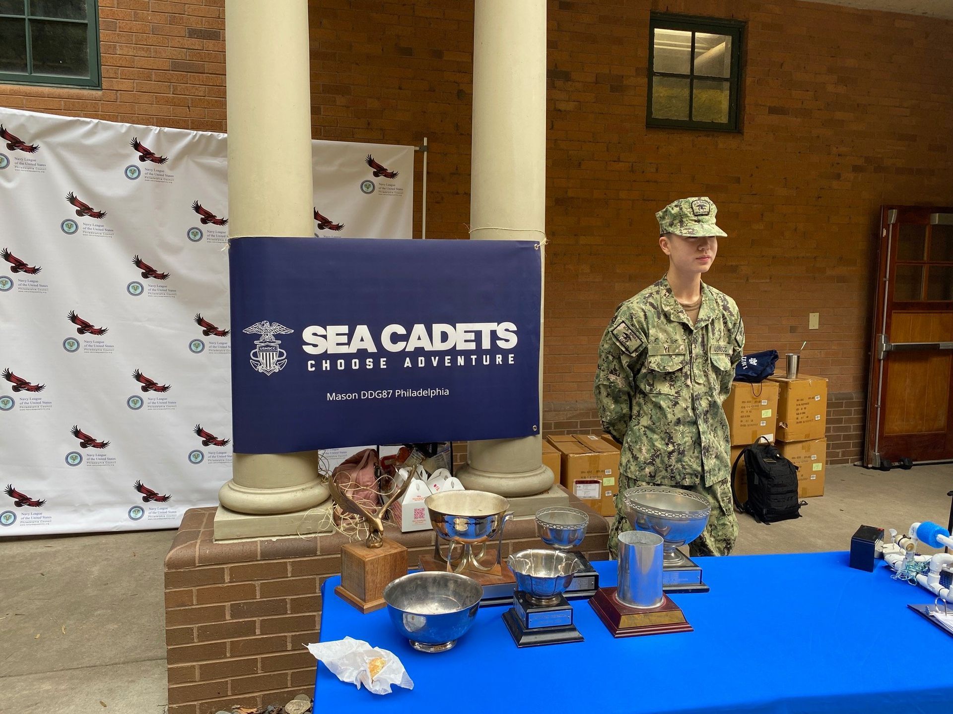 A man in a sea cadets uniform stands in front of a table