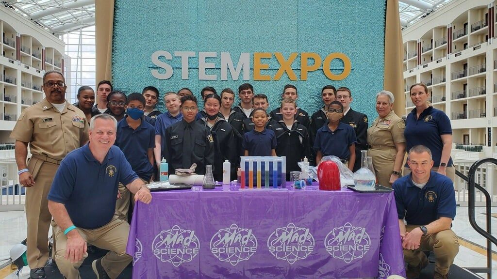A group of people are posing for a picture in front of a sign that says Stem Expo.