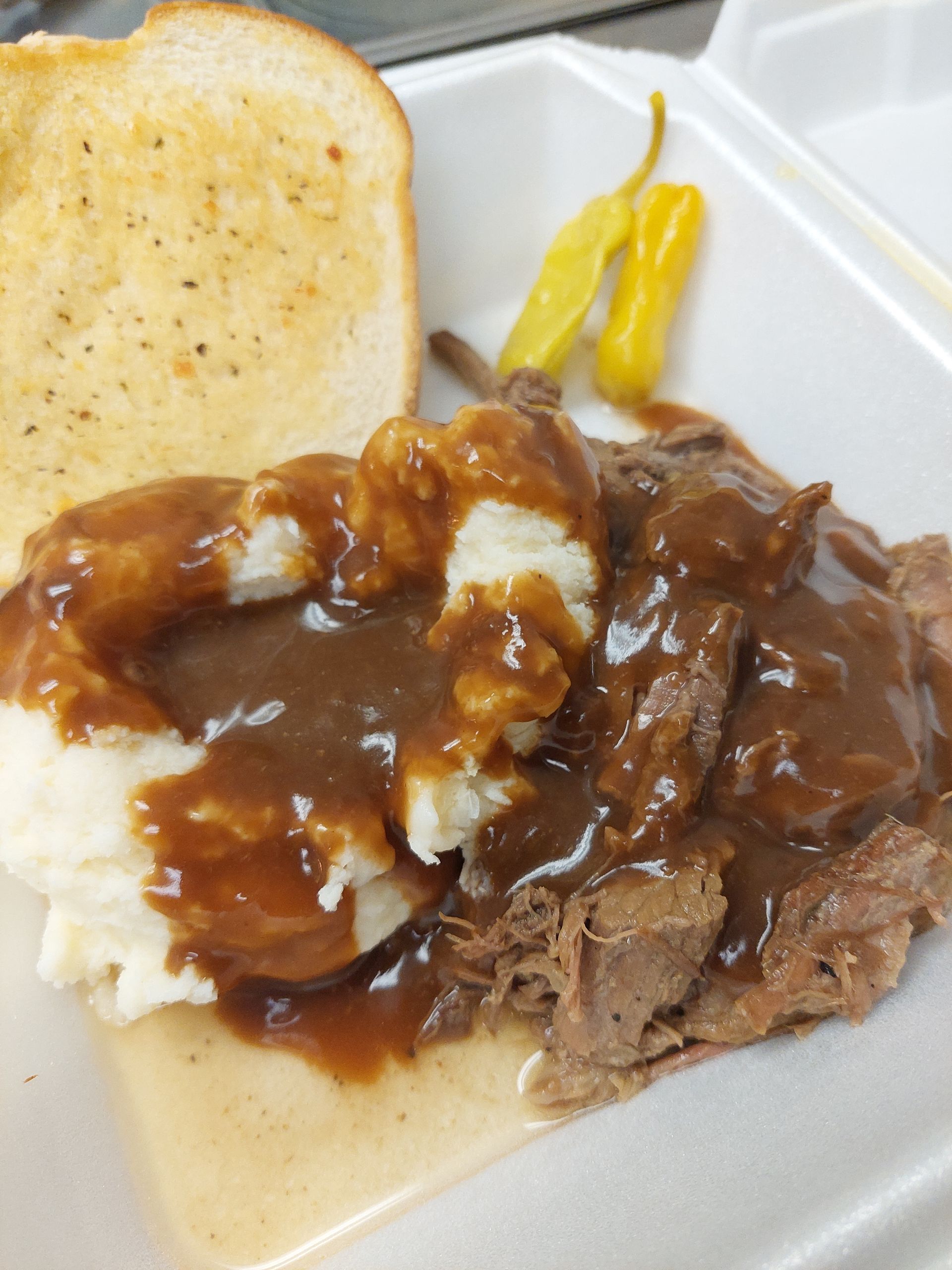 A beef sandwich with mashed potatoes and gravy on a styrofoam container