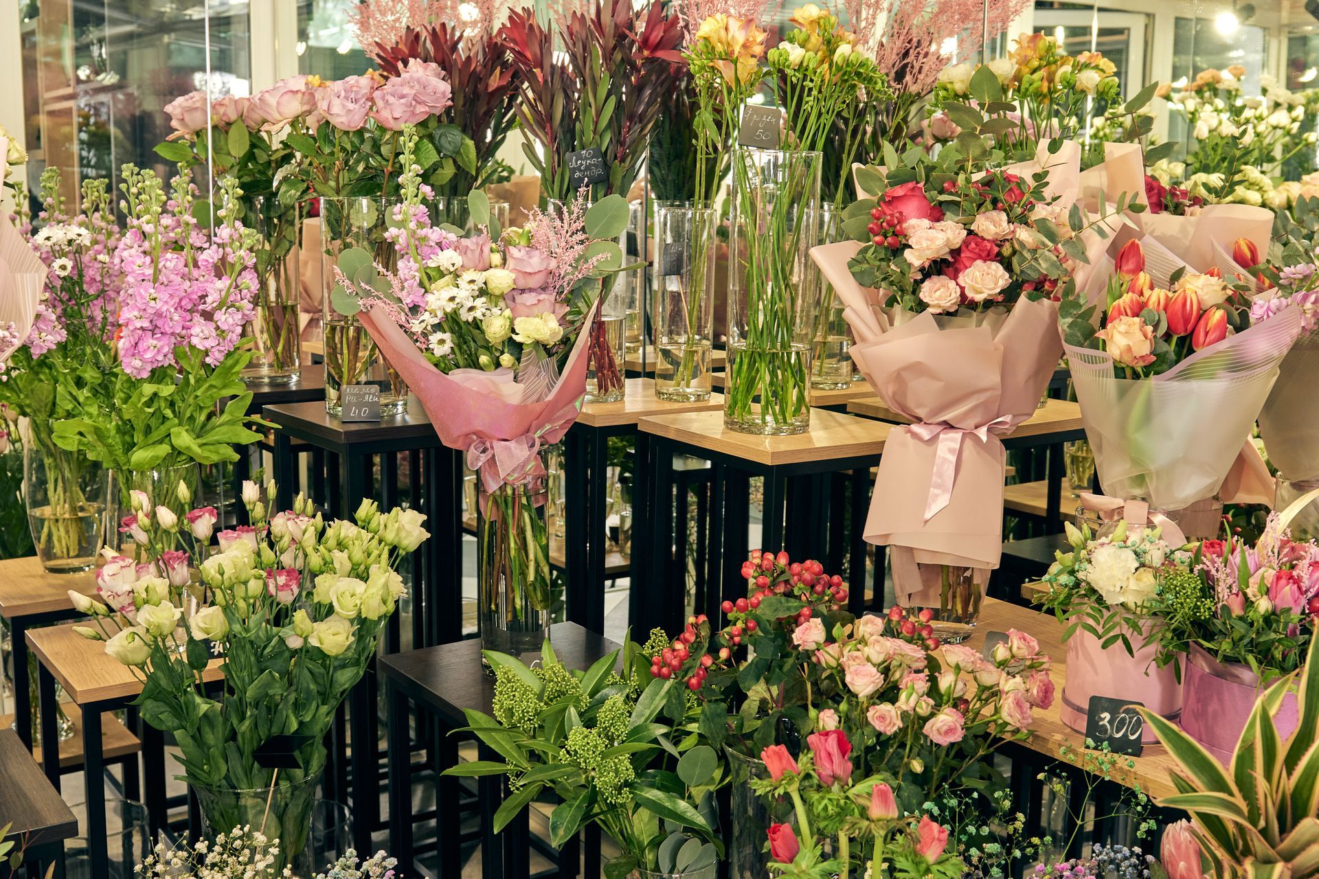 A bunch of flowers are sitting on tables in a flower shop.