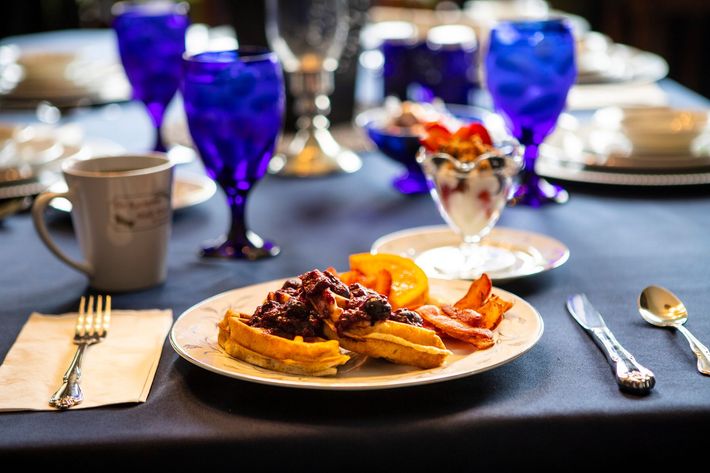 A plate of food is on a table with blue glasses.