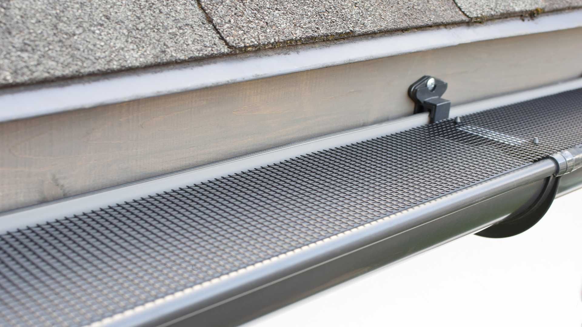 Close-up of a roof gutter guard with a leaf mesh under the eaves.