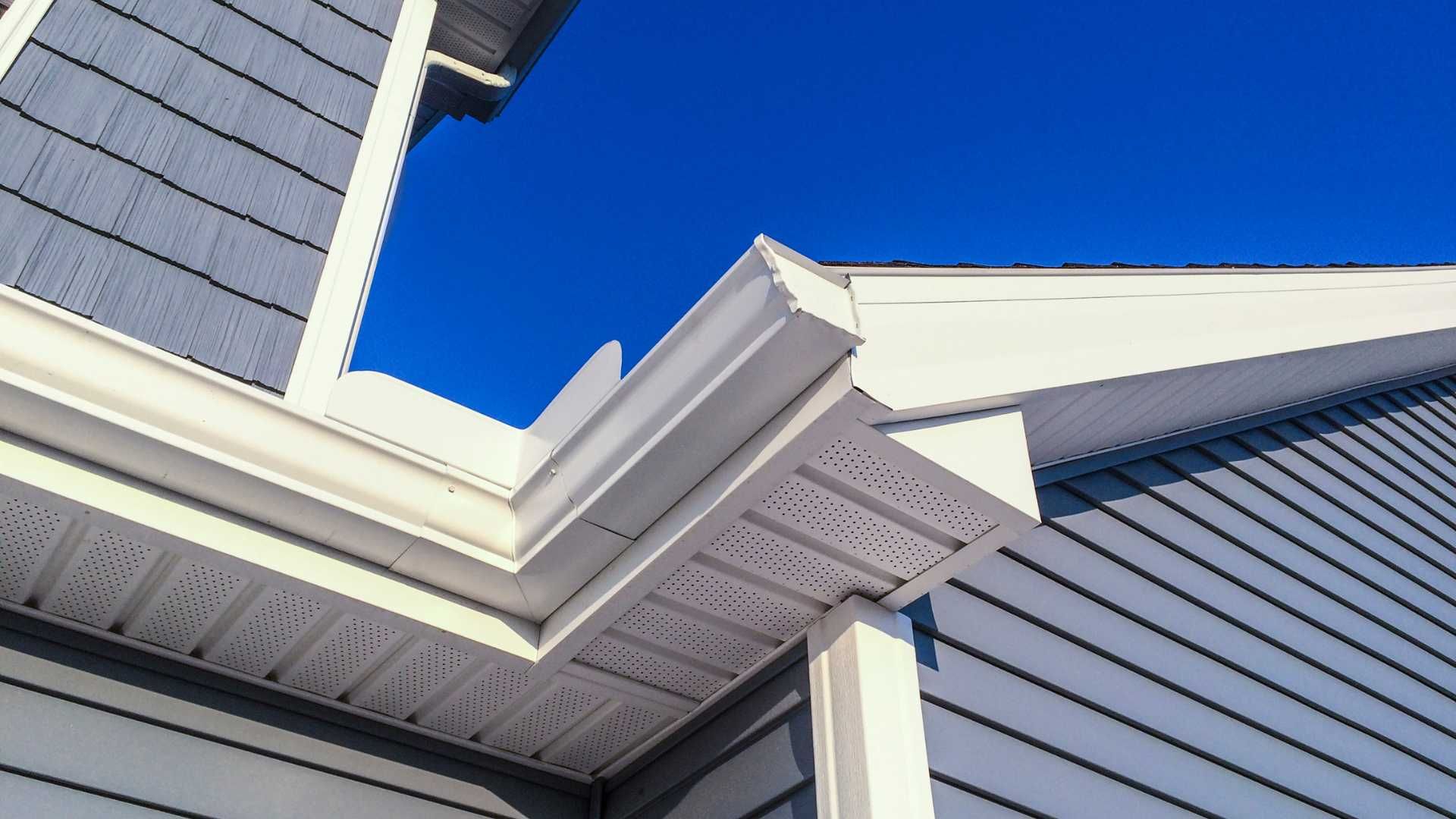 White house eaves and blue siding against a bright blue sky