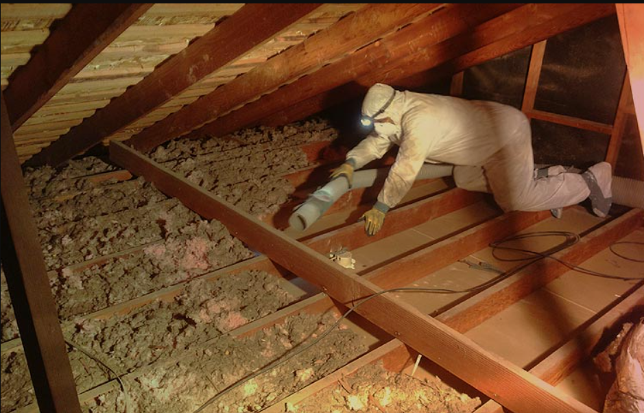 Attic interior with spray foam insulation on walls and rafters, unfinished floor and a window.