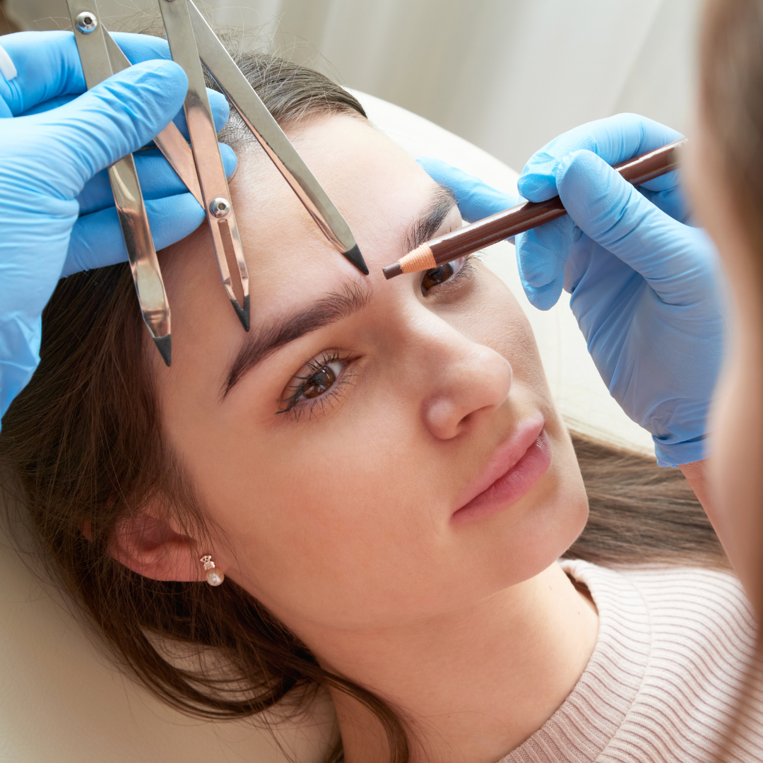 Eyebrow mapping: a person with hands in blue gloves measuring and marking eyebrow shape with tools and pencil.