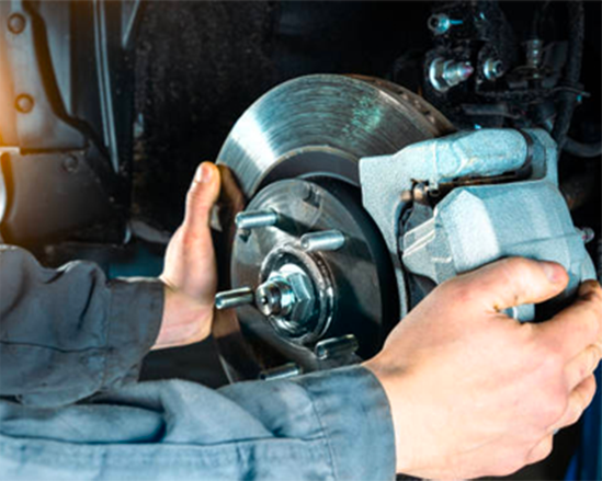 Mechanic replacing a car brake rotor with a caliper in a garage