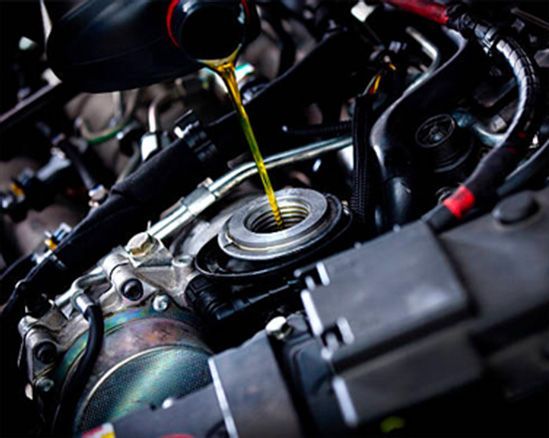 Motor oil being poured into a car engine through the oil cap opening