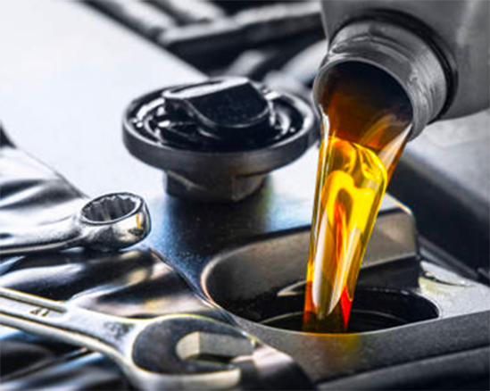 Motor oil being poured into an engine compartment with a dipstick nearby