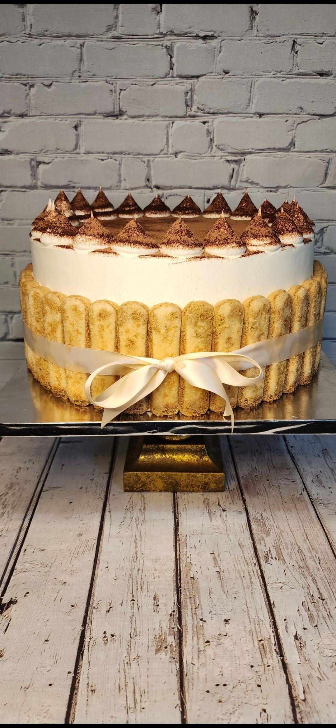 A cake is sitting on top of a glass cake stand on a wooden table.