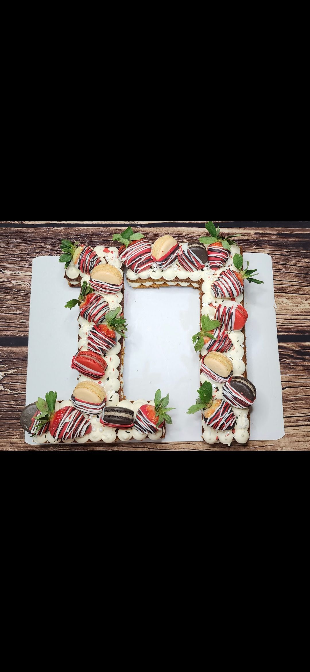 A cake in the shape of a letter n with strawberries on it.
