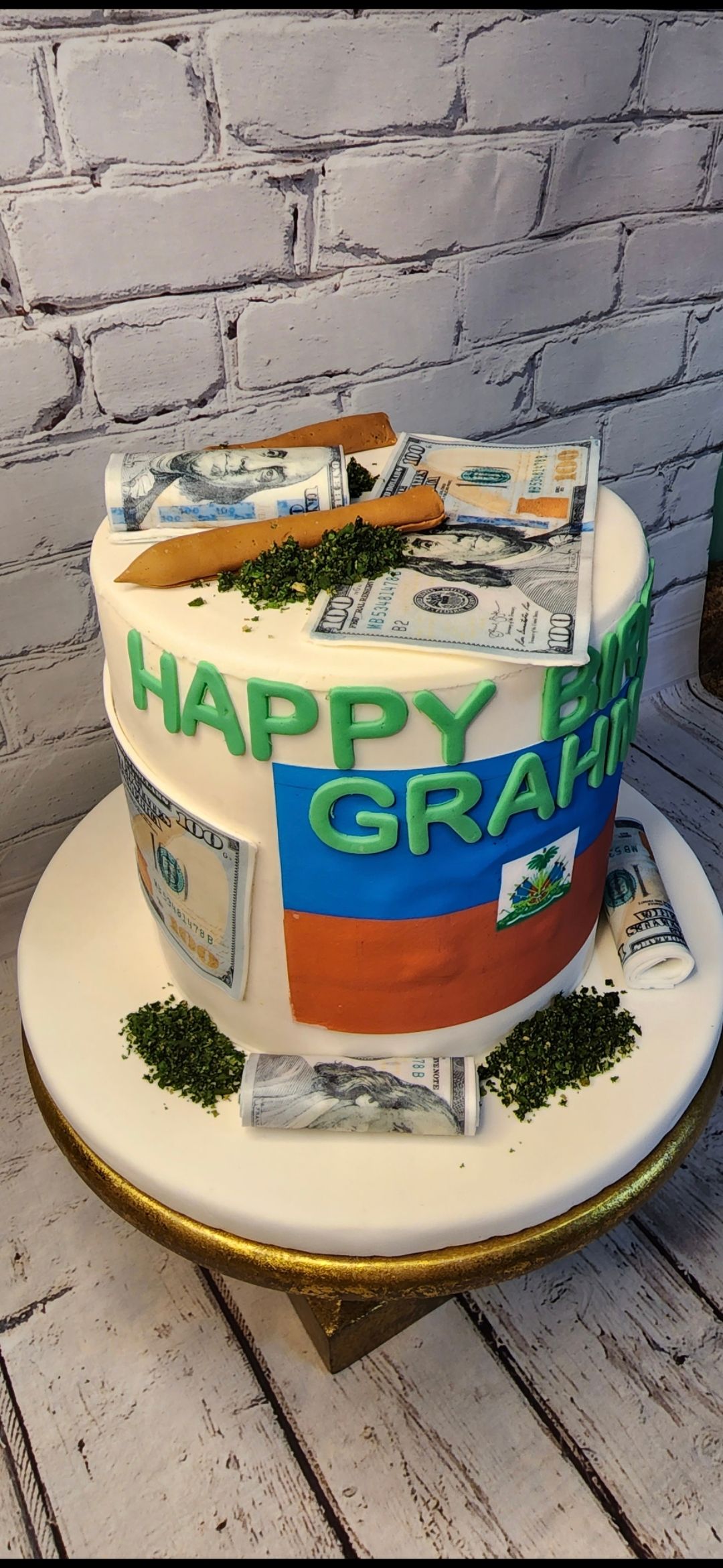 A cake with money and a pencil on it is on a table.