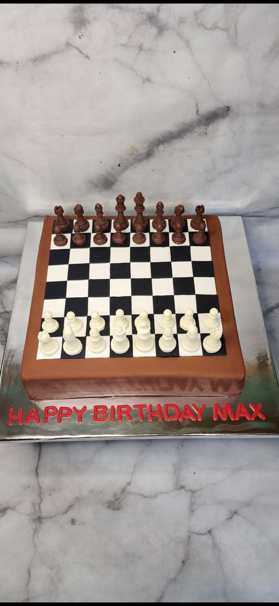 A cake that looks like a chess board with chess pieces on it.