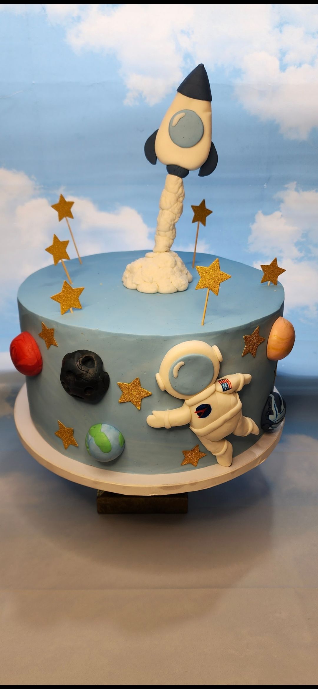 A cake with a rocket , astronaut , planets and stars on it.
