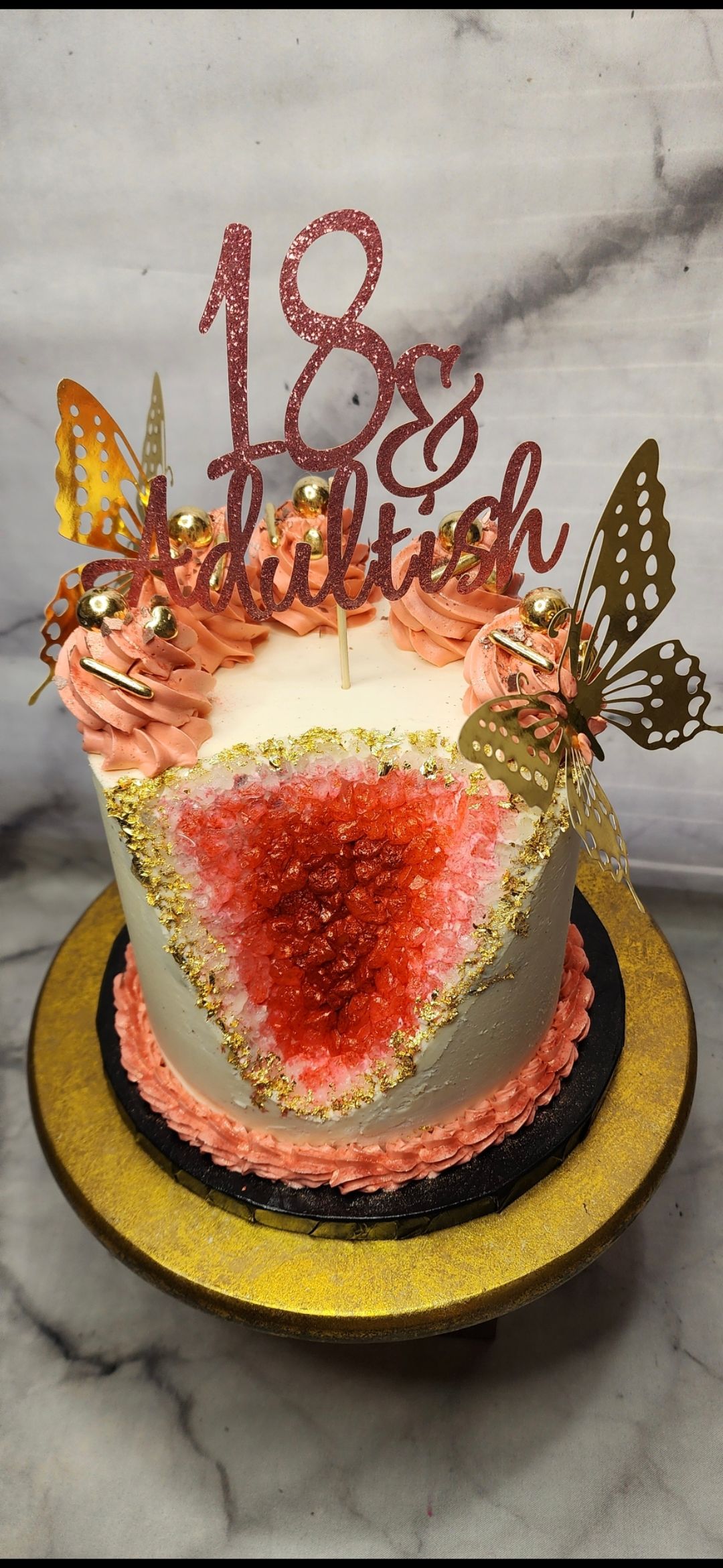 A cake with a heart shaped hole in the middle is on a gold plate.