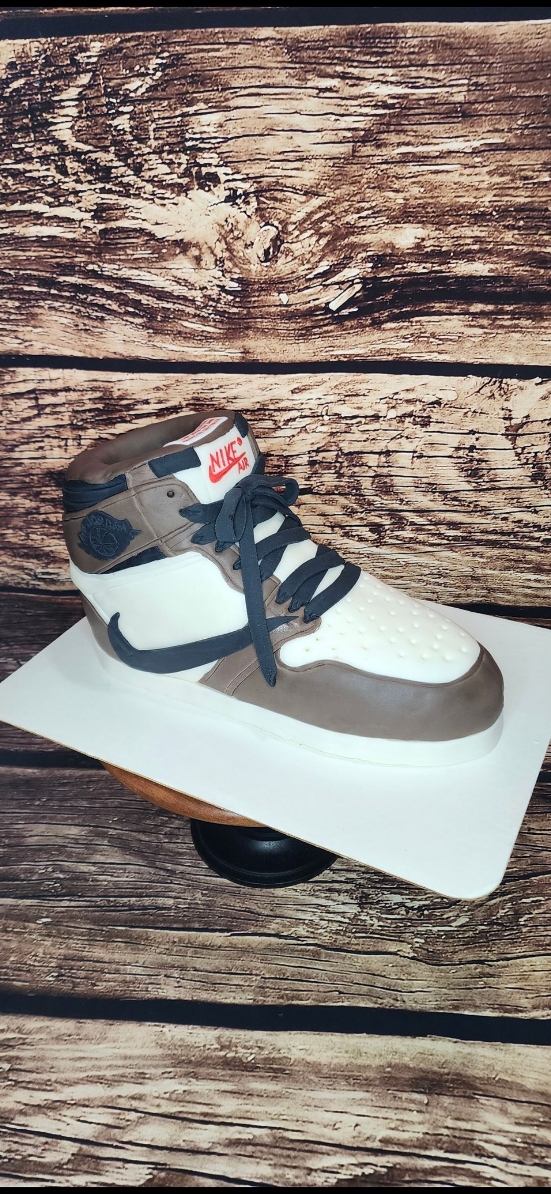 A cake in the shape of a shoe is sitting on a wooden table.