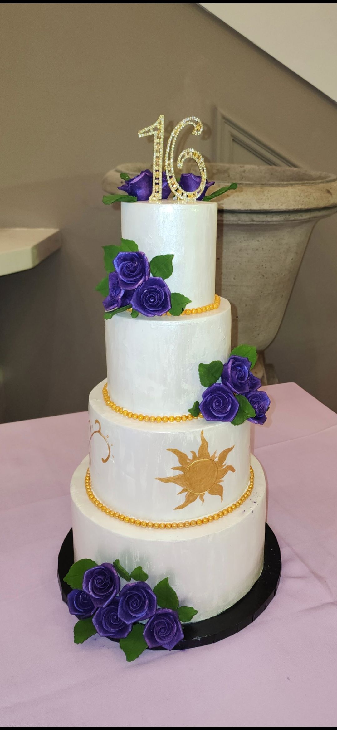 A white cake with purple flowers and the number 16 on top