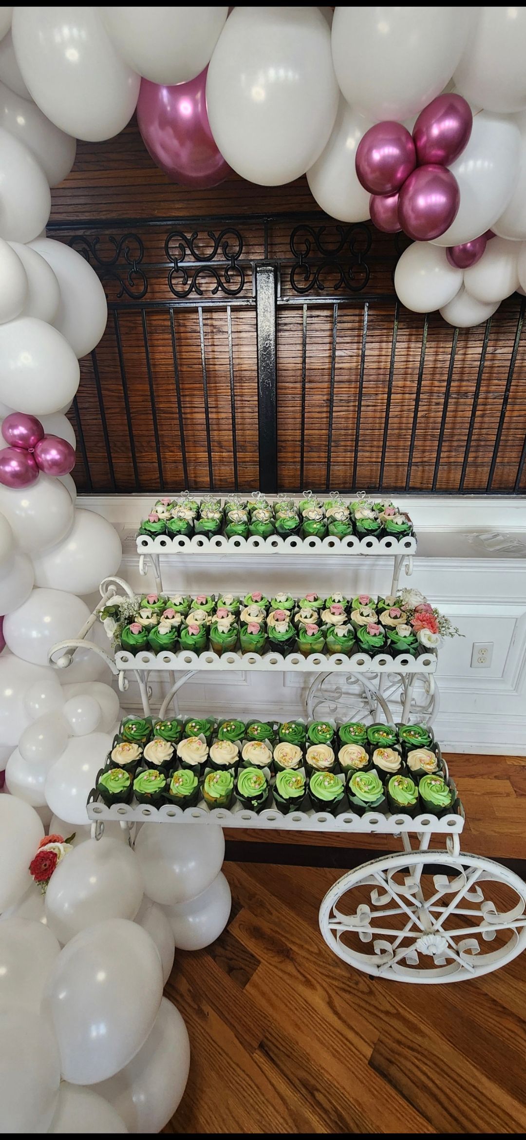 A table with cupcakes and balloons on it.