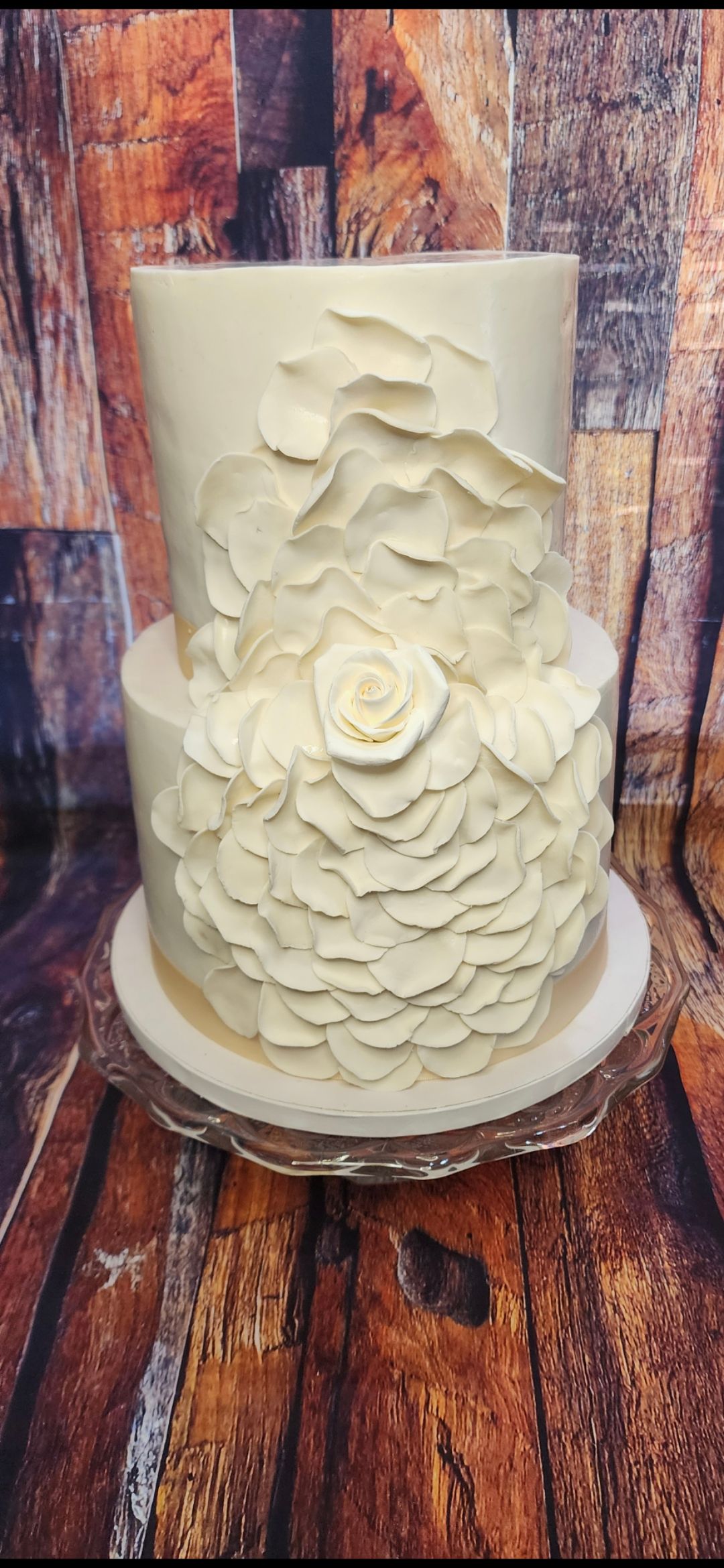 A white wedding cake is sitting on top of a wooden table.