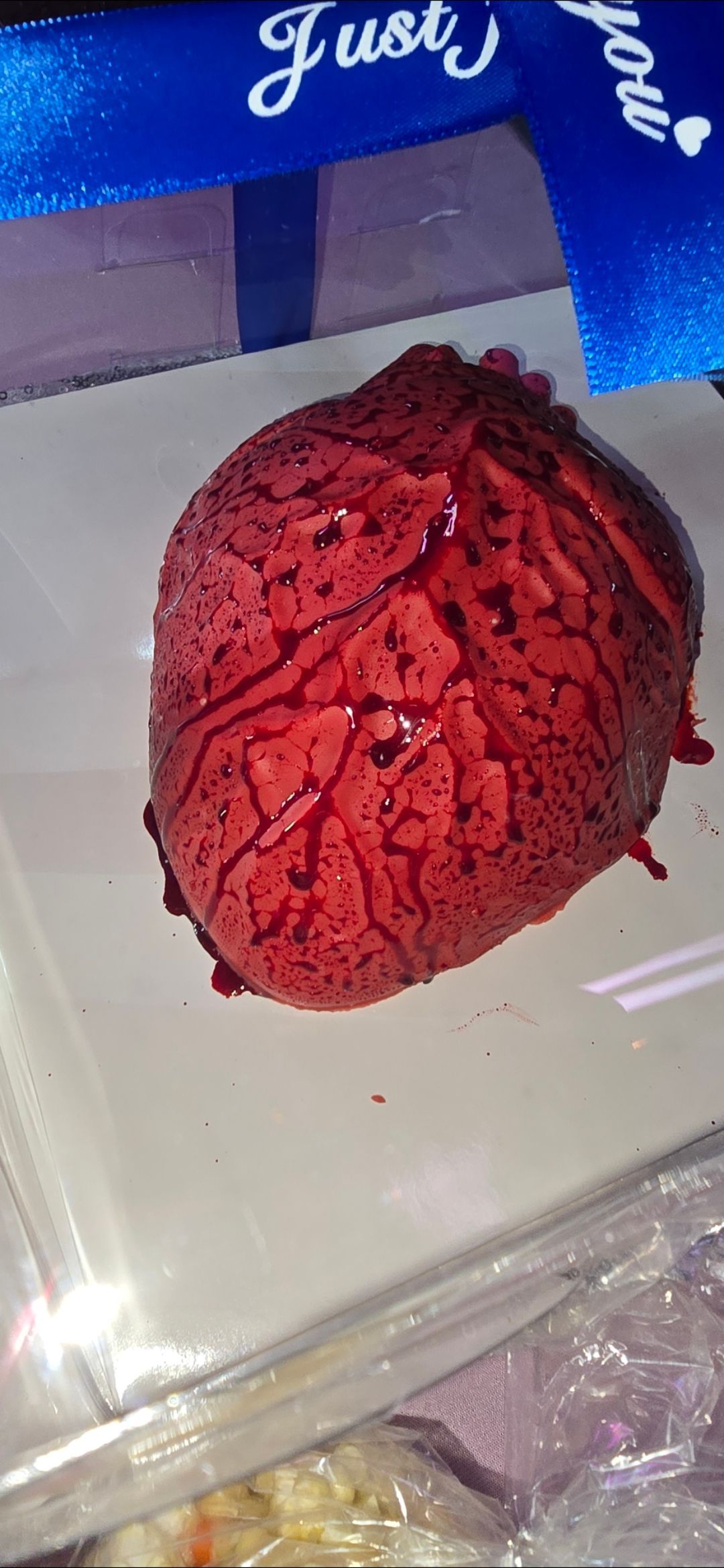 A red heart shaped cake is sitting on a white plate.