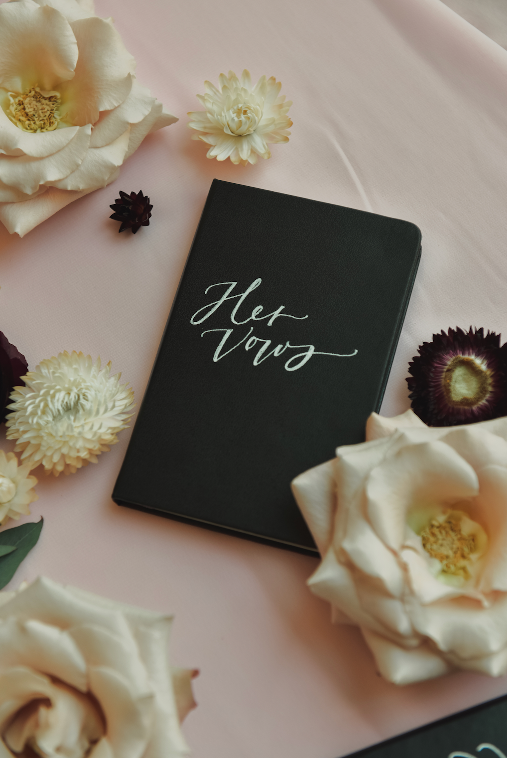 A black book with the word her on it is surrounded by flowers