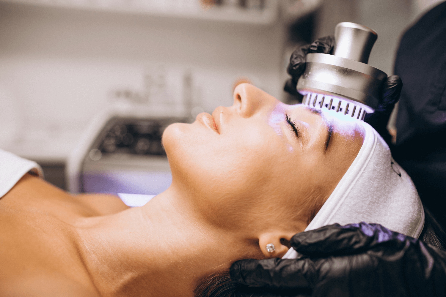 Woman receiving a professional facial treatment with advanced skincare device at a medical spa.