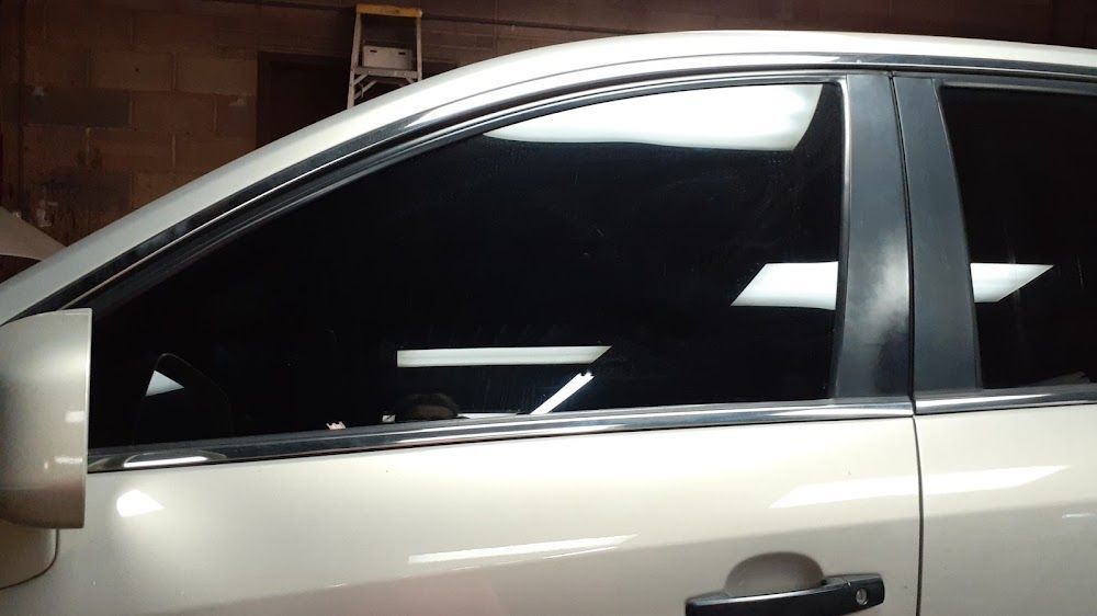 Side view of a white car with tinted windows parked indoors against a brick wall