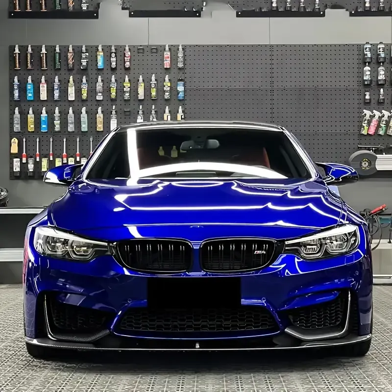 Blue BMW sports car in a garage, front view against a wall of detailing bottles.