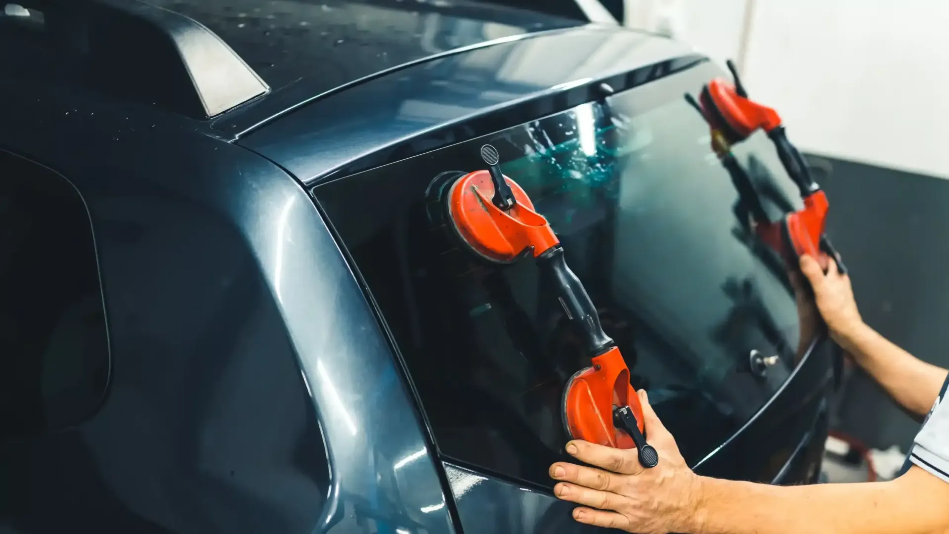 Person using suction cups to install or remove a dark-tinted car window film