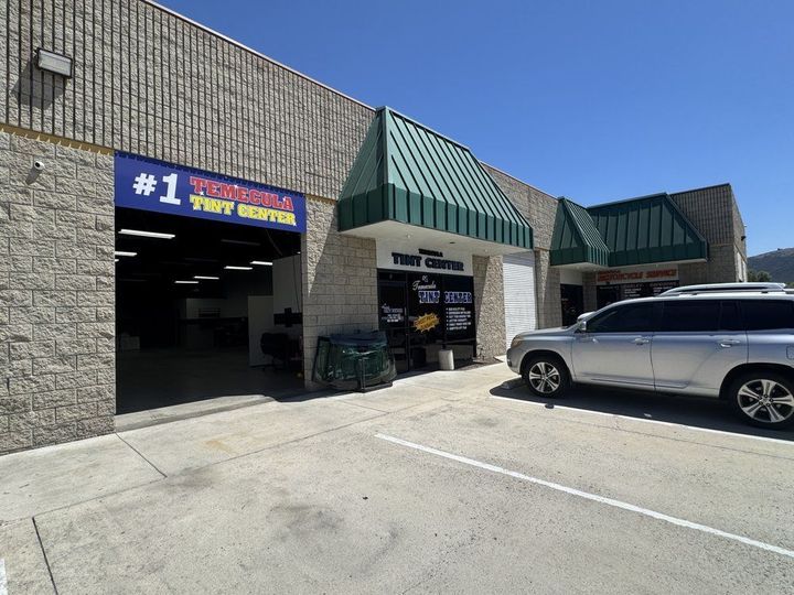 Auto service storefront with green awnings and a silver SUV parked outside