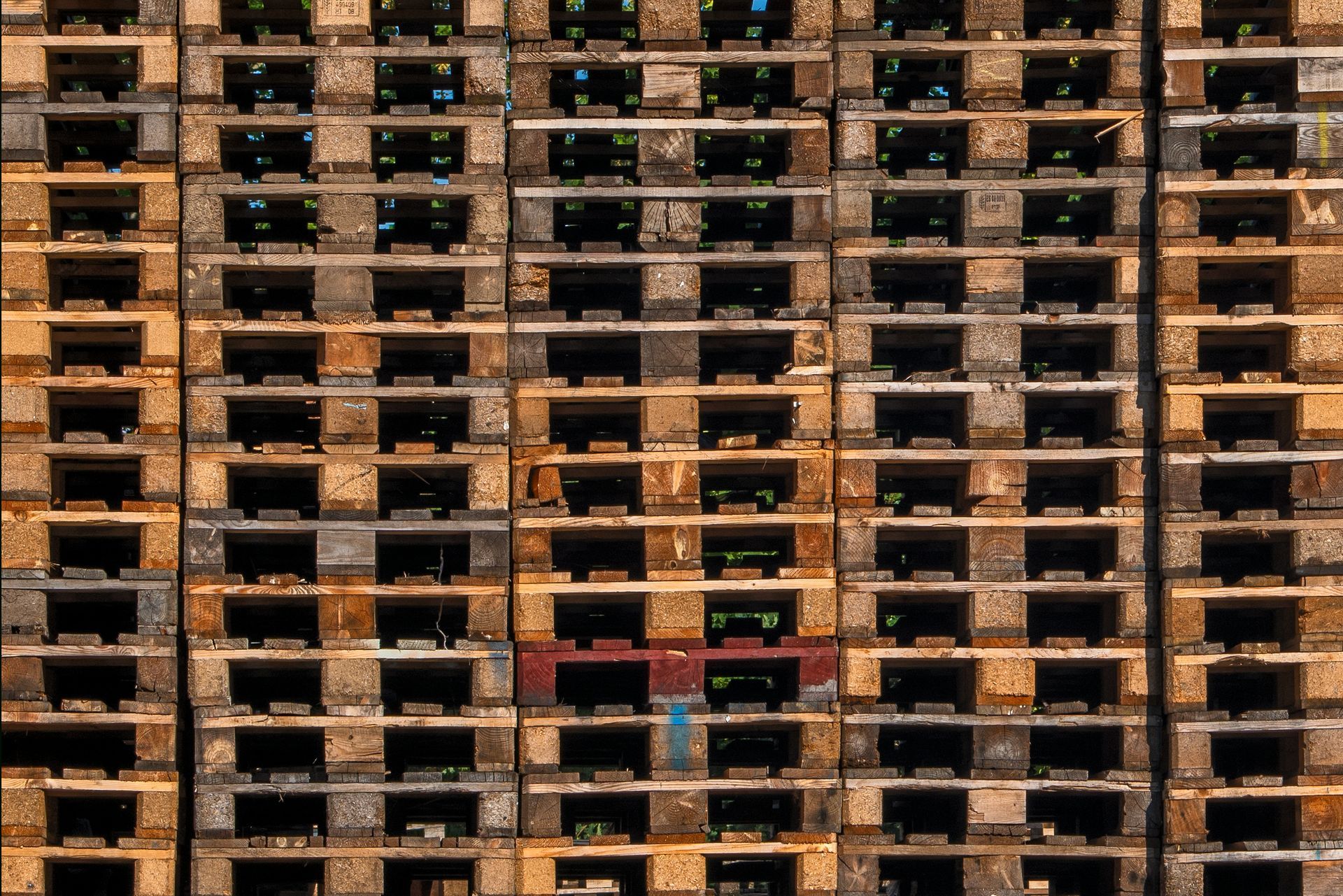 Stack of weathered wooden pallets in a warehouse setting.