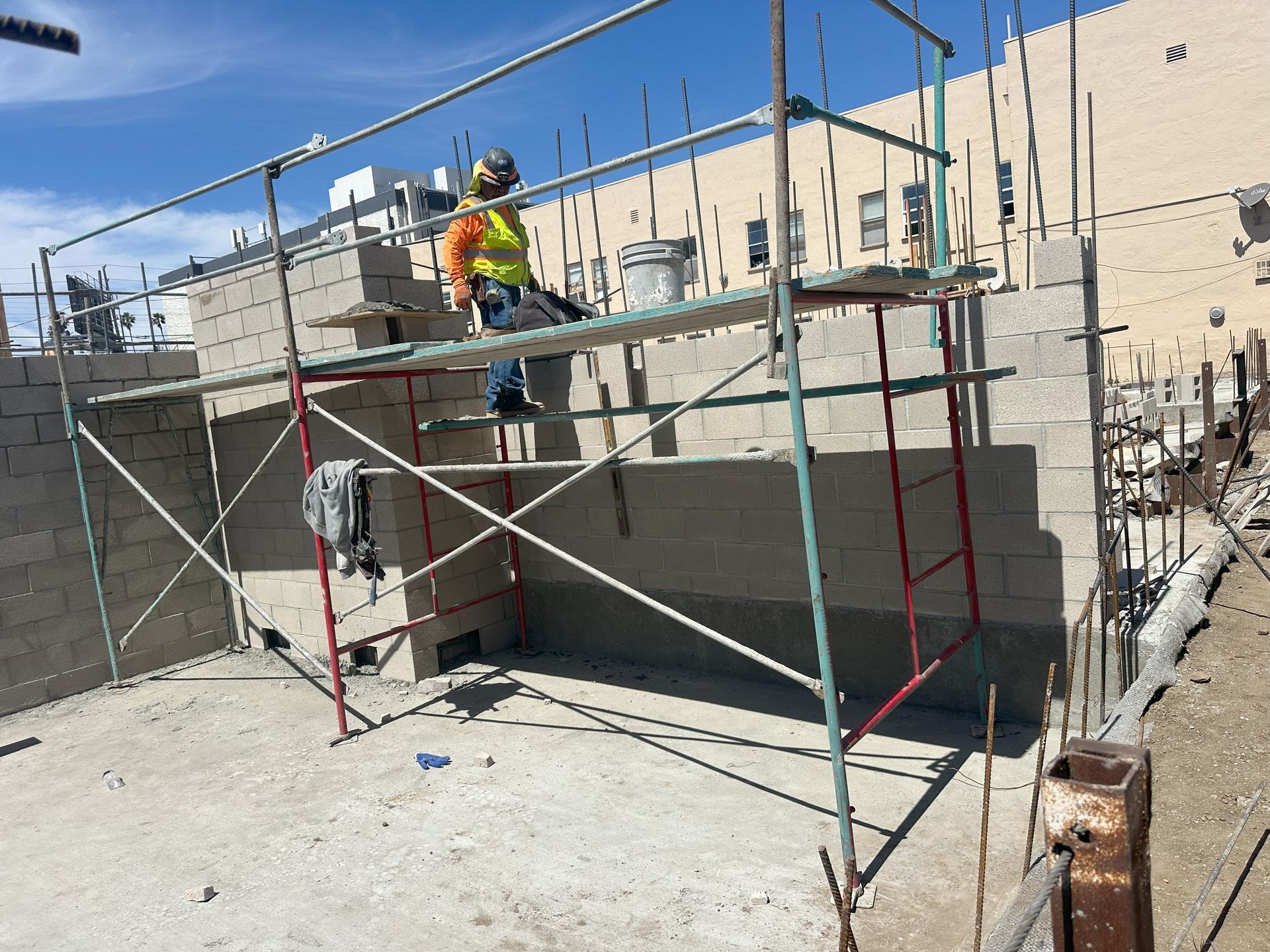 Construction worker on scaffolding laying cinder blocks.