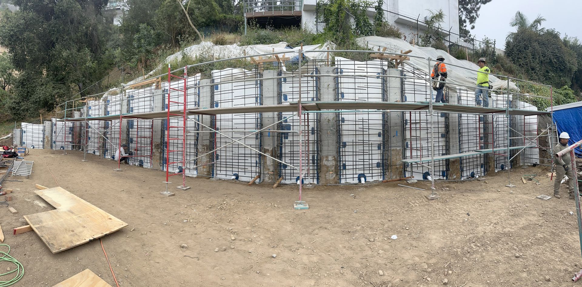 Construction site with workers building a retaining wall on a hillside.